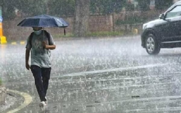 देश की राजधानी दिल्ली में बारिश में छत्री लेकर चलती एक बाला.