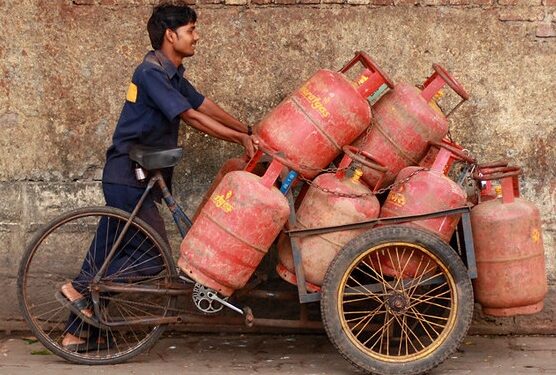 गैस सिलेंडर के साथ हर्षित मुद्रा में गैंस पहुंचाने वाला.